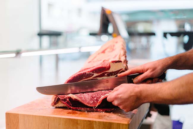 Carnicería - Charcutería Monedero persona cortando carne